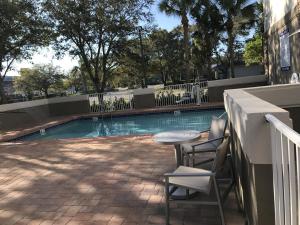 uma piscina com cadeiras e uma mesa ao lado de um edifício em Holiday Inn Express - Naples South - I-75, an IHG Hotel em Naples