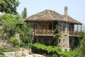 stary kamienny dom z balkonem na wzgórzu w obiekcie Frixos House w mieście Elati Zagori