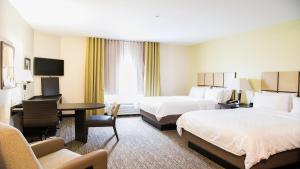 a hotel room with two beds and a desk at Candlewood Suites Bay City by IHG in Bay City