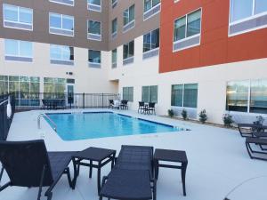 una piscina en un edificio con mesas y sillas en Holiday Inn Express & Suites - Carrollton West, an IHG Hotel, en Carrollton