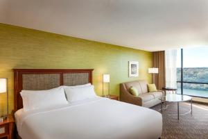 a hotel room with a bed, chair, and nightstand at Holiday Inn Austin -Town Lake, an IHG Hotel in Austin