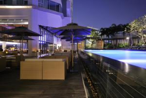 a swimming pool with tables and umbrellas next to a building at JC Kevin Sathorn Bangkok Hotel in Bangkok