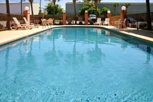 una gran piscina azul con sillas y mesas. en Holiday Inn Express - Biloxi - Beach Blvd, an IHG Hotel, en Biloxi