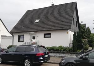 a black car parked in front of a white house at Ferienwohnung Sonnwald in Düsseldorf