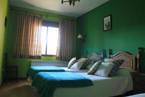2 Betten in einem Schlafzimmer mit grünen Wänden und einem Fenster in der Unterkunft Casa Rural Baobab in Romancos