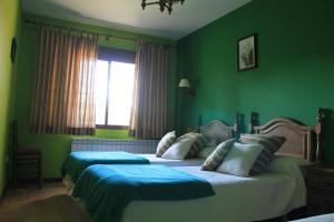 two beds in a bedroom with green walls and a window at Casa Rural Baobab in Romancos +30 photos