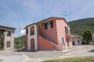 ein rosafarbenes Haus mit einer Treppe an der Seite in der Unterkunft Alloggio vocabolo San Sebastiano in Massa Martana