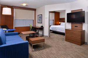 une chambre d'hôtel avec un canapé, un lit et une télévision dans l'établissement Holiday Inn Express & Suites Buffalo Downtown, an IHG Hotel, à Buffalo