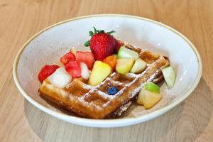 a bowl of waffles with fruit on a table at Hotel Indigo Berlin - East Side Gallery, an IHG Hotel in Berlin