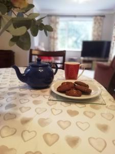 einen Teller Kekse und eine Teekanne auf dem Tisch in der Unterkunft Wedgewood Annexe - All the comforts of home in Mere