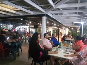 een groep mensen die aan tafel zitten in een restaurant bij Hotel Millenia Samoa in Apia