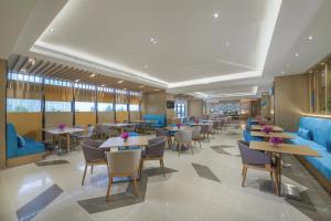 un restaurant avec des tables, des chaises et un mobilier bleu dans l'établissement Holiday Inn Express Zhengzhou Longzi Lake, an IHG Hotel, à Yaoqiao