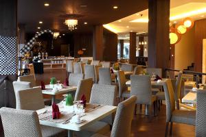 a dining room with tables and chairs and a bar at Serela Kuta by KAGUM Hotels in Kuta