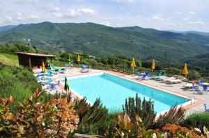 a swimming pool with chairs and umbrellas and mountains at Universal Harmony Agriturismo in Dicomano