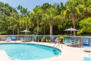 una piscina con sedie, ombrelloni e palme di Holiday Inn Express Charleston US Highway 17 & I-526 by IHG a Charleston