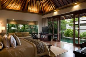 a bedroom with a bed and a tv and a pool at The Royal Santrian in Nusa Dua