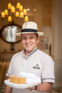 a man in a hat holding a tray of juice at Hotel del Parque in Guayaquil