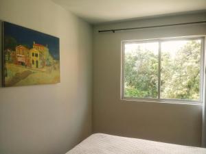 a bedroom with a window and a painting on the wall at Aconchegante e próximo à natureza! in Curitiba