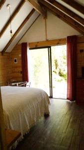 een slaapkamer met een bed en een groot raam bij Posada de Expediciones Kahuel in Chaitén