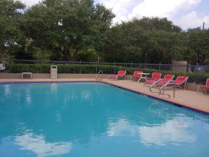 a swimming pool with red chairs next to a fence at Holiday Inn Express Hotel & Suites Columbus, an IHG Hotel in Columbus