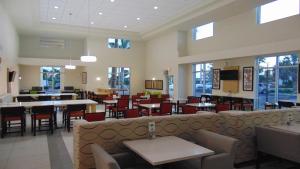 a dining room with tables and chairs and a restaurant at Holiday Inn Express & Suites Boynton Beach East, an IHG Hotel in Boynton Beach