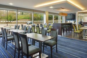 a restaurant with tables and chairs and a television at Holiday Inn Express Cambridge Duxford M11 Jct 10, an IHG Hotel in Cambridge
