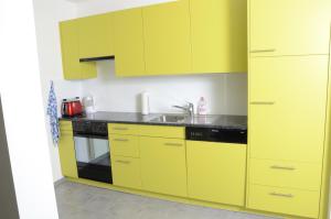 a kitchen with yellow cabinets and a sink at Guesthouse Casa Esperanza Basel in Basel