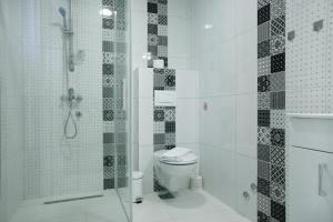 a white bathroom with a shower and a toilet at Fine Suites in Niš