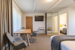 ein Hotelzimmer mit einem Schreibtisch, Stühlen und einem Bett in der Unterkunft Mick O'Sheas in Hackham