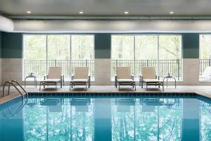 uma piscina num hotel com cadeiras e janelas em Holiday Inn Express & Suites - Yorkville, an IHG Hotel em Yorkville