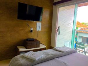a bedroom with a bed and a flat screen tv at Pousada Pinheiro in Campos dos Goytacazes