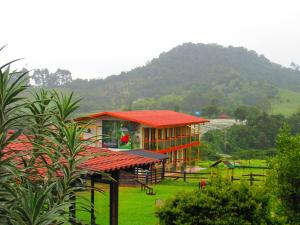 una casa con techo rojo en un campo verde en Mamatina Hotel, en Santa Rosa de Cabal