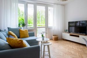 salon z niebieską kanapą i telewizorem w obiekcie CRISTINE APARTMENT w Warszawie