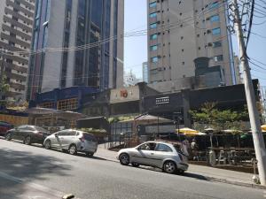 three cars parked on a city street with tall buildings at Hotel Recanto das Perdizes in São Paulo