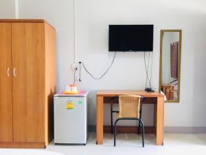a room with a table and a refrigerator and a television at Pantip Residence in Nan
