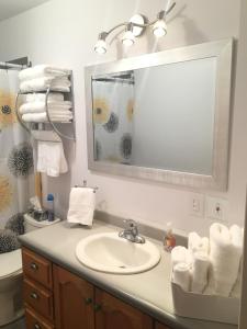 Un baño con lavabo, espejo y toallas. en Le Milka II, en Longueuil