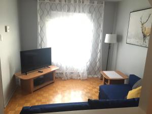 sala de estar con TV y sofá azul en Le Milka II en Longueuil