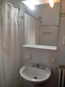 a white bathroom with a sink and a mirror at Hotel Alonso in Río Gallegos