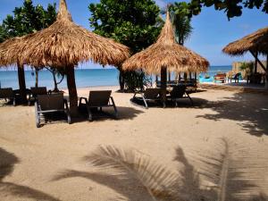 a beach with chairs and straw umbrellas and the ocean at The Lazy Lodge in Ko Lanta