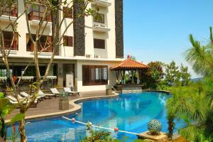 a swimming pool in front of a building with a gazebo at The Grand Hill Resort-Hotel in Puncak