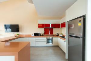 a kitchen with red and white cabinets and a refrigerator at Teetara Villa Patong in Patong Beach