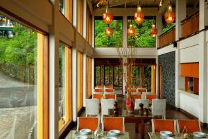 un comedor con mesas, sillas y ventanas en The Grand Hill Resort-Hotel, en Puncak