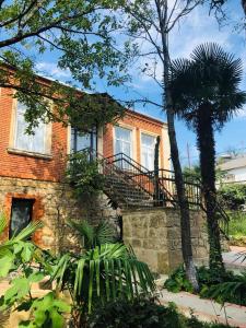Casa de ladrillo con balcón y palmera en Guest House Hello en Kutaisi