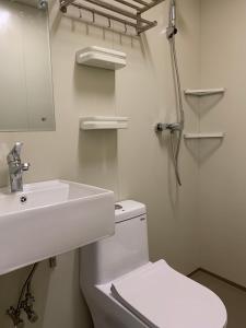 a white bathroom with a toilet and a sink at Chalet Madarao in Iiyama