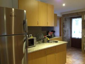 a kitchen with a stainless steel refrigerator and a sink at Alojamiento Pazos in Cea +55 photos
