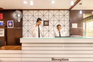 two women talking on a cell phone behind a counter at Hotel Satkar in Surat