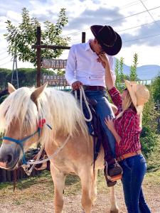 un homme est assis sur un cheval avec une fille dans l'établissement La Tenuta del Campo di Sopra, à Patrica