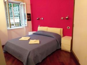 um quarto vermelho com uma cama com duas toalhas em Vacanze Romane con giardino em Roma
