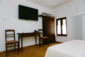 a bedroom with a desk and a television on the wall at Locanda Al Confin - Osteria Le Piere in Pigozzo