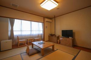 a living room with a table and a television at 湯布院 旅館 やまなみ Ryokan YAMANAMI in Yufuin